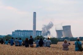 A field of people watch from a distance as the iconic cooling towers of Didcot A coal power station are demolished